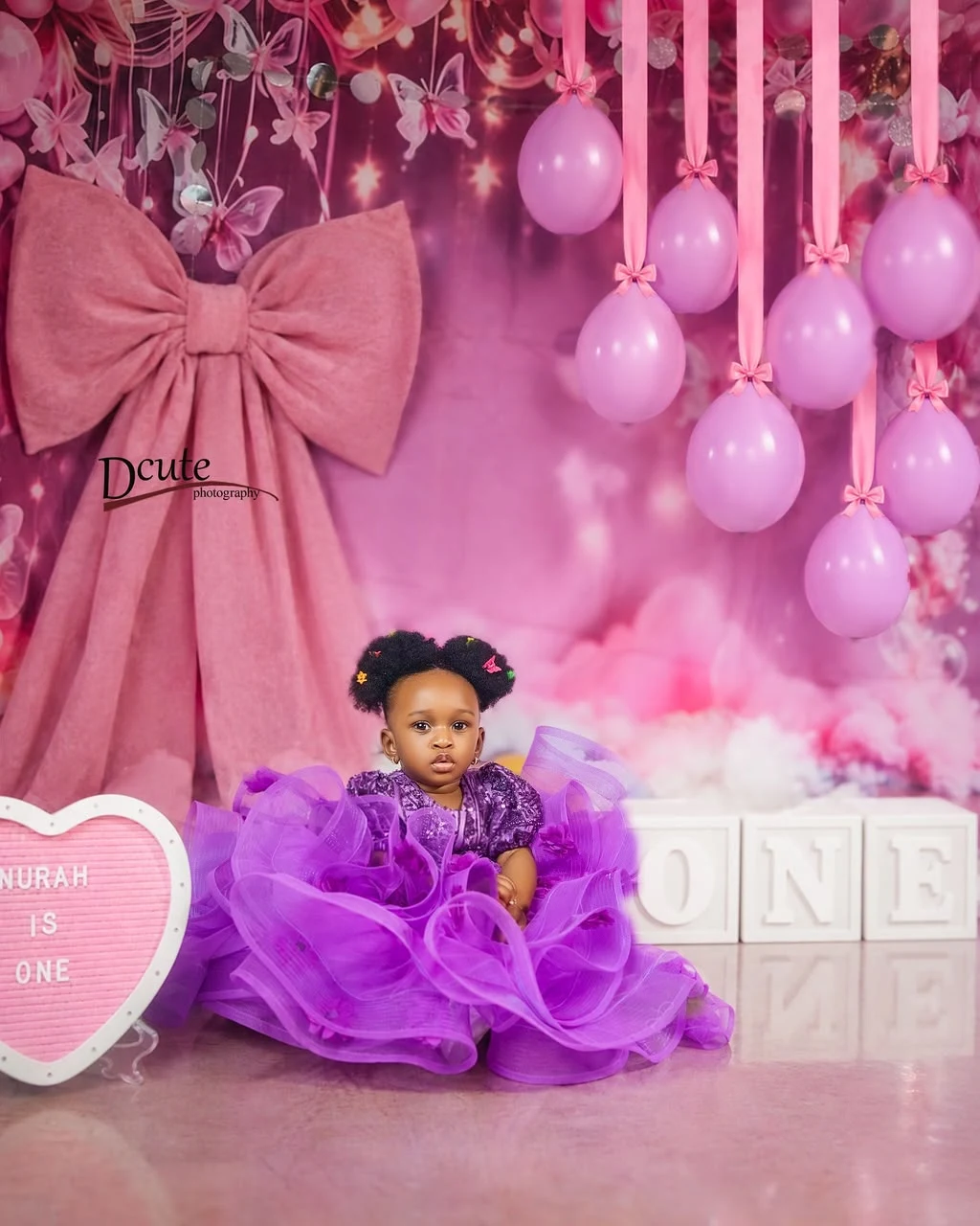 Noorah celebrating her first birthday with pink balloons